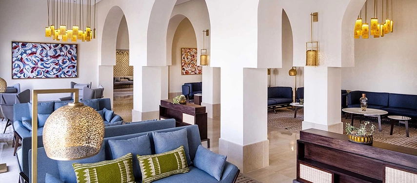 Bright lounge area at The Residence Douz with white archways, blue seating, and golden hanging lamps.
