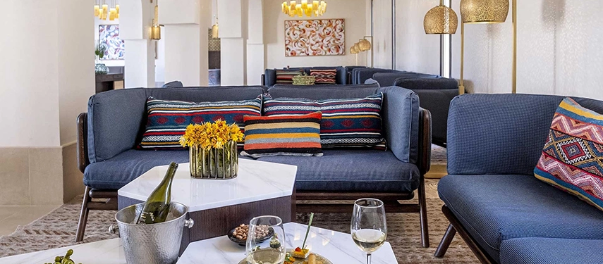 Elegant lounge with deep blue sofas, patterned cushions, and golden pendant lights at The Residence Douz.