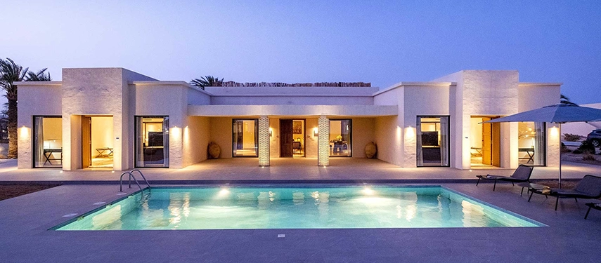 Private luxury villa at The Residence Douz with its own illuminated pool at dusk.