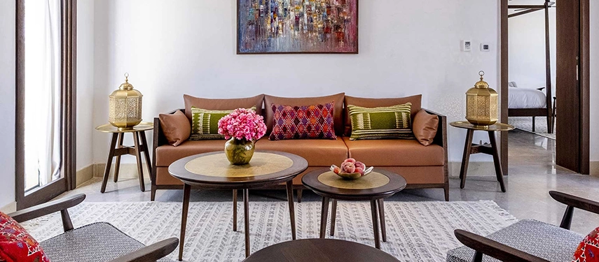 Bright villa lounge at The Residence Douz with a terracotta sofa, colourful cushions, and golden lanterns.