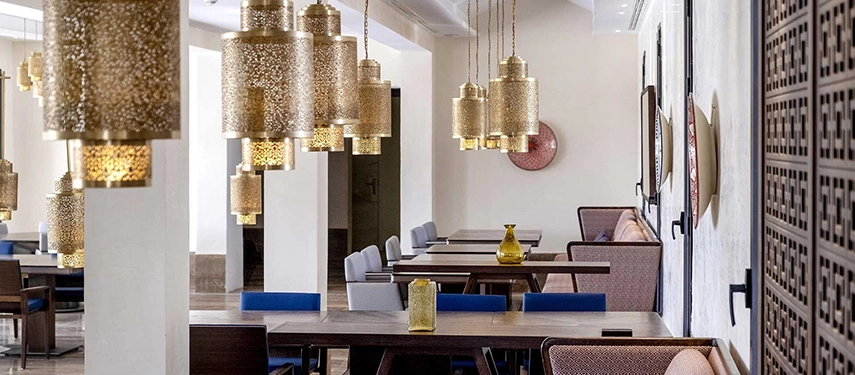 Dining area at Talis Restaurant with golden hanging lanterns, dark wood tables, and soft ambient lighting.
