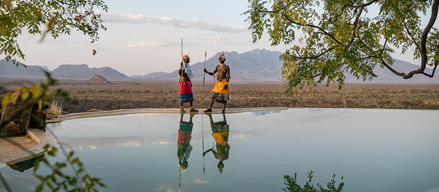 Two Samburu warriors reflected in the water of Reteti House’s infinity pool at sunset.