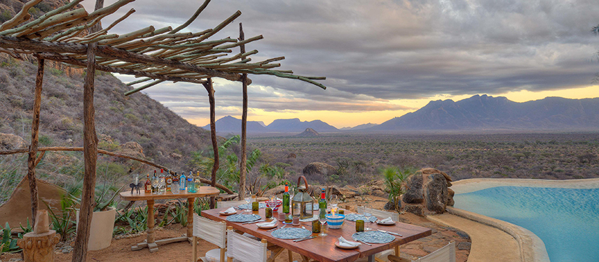 Al fresco dining setup beside the pool with panoramic views of the Namunyak Conservancy hills.