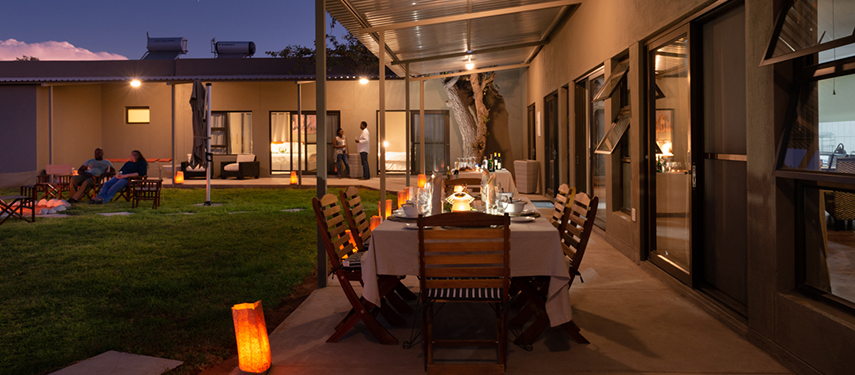 Guests relaxing on the lawn and dining al fresco under lantern light at Safari House in the evening.