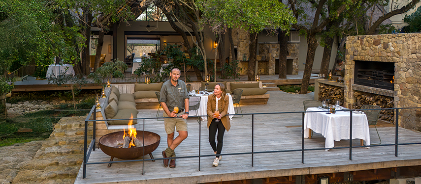 Evening dining setup with fire pit and lanterns, creating an intimate outdoor atmosphere beneath the trees.