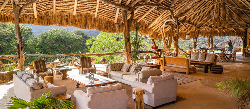 The open-air main lounge at Sarara Treehouses with plush sofas, rustic furnishings, and panoramic views of the surrounding forested hills.