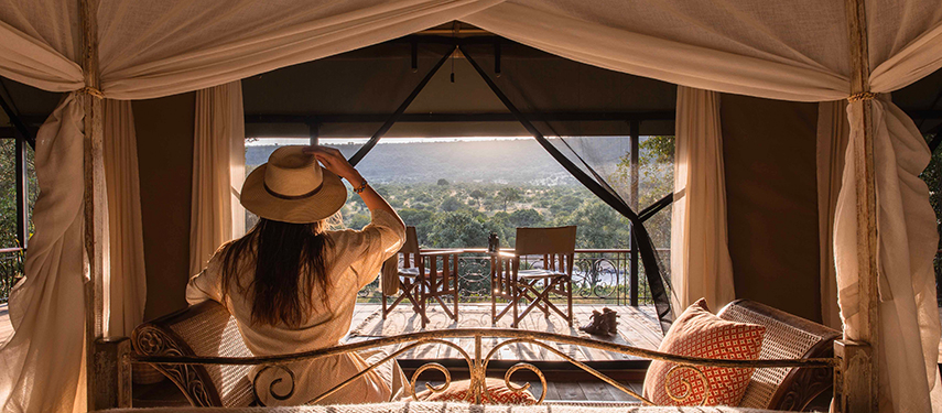 View from inside a tent at Serian ‘The Original’, with a woman gazing out at the landscape from a wrought-iron bed.