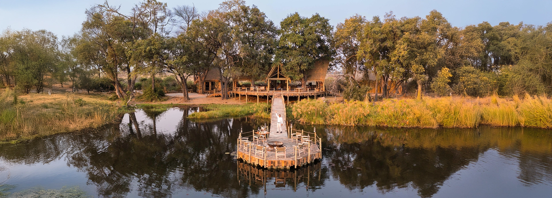 A host waves from the boma deck of the luxurious Sitatunga Private Island lodge in th eOkavango Delta