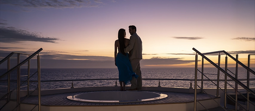 Couple enjoying sunset beside the jacuzzi on the Hermes Galápagos Mega Catamaran’s upper deck.