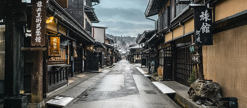 A snow-dusted Edo-period street in Takayama lined with traditional wooden townhouses, capturing the quiet beauty of historic mountain Japan.