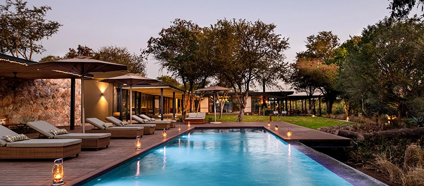 The main pool deck illuminated by lanterns at twilight, creating a warm and inviting atmosphere.