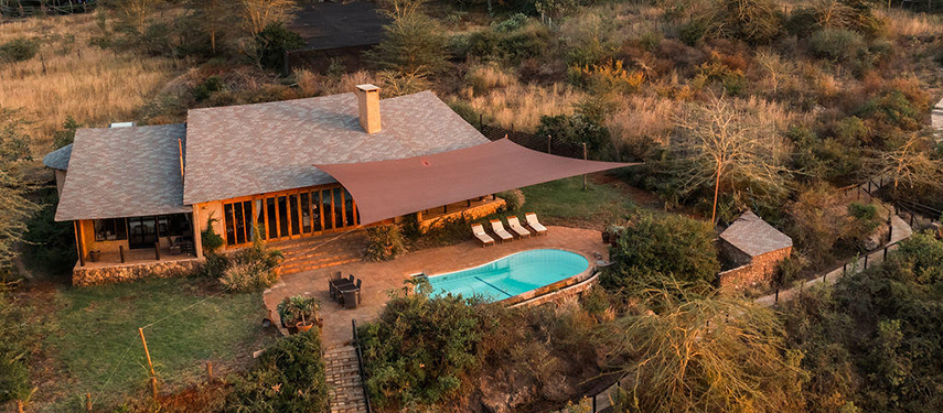 An aerial view of The Emakoko’s main lodge and swimming pool, surrounded by bushland and golden light.
