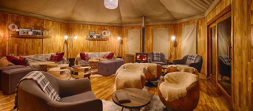 Cosy lounge at The Highlands with wood panelling and a glowing wood-burning stove