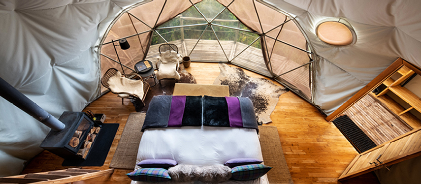 Overhead view of a Highlands dome bedroom with glass frontage and wood-burning stove