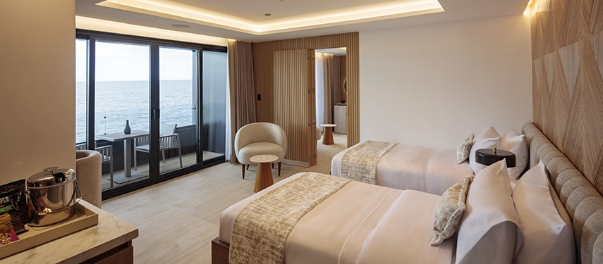 Modern twin suite with private balcony overlooking the sea aboard the Hermes Galápagos Mega Catamaran.