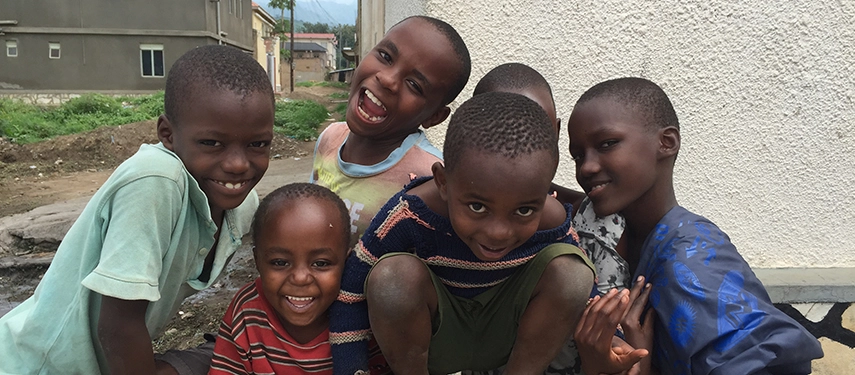 Smiling Ugandan children posing joyfully outside a local home
