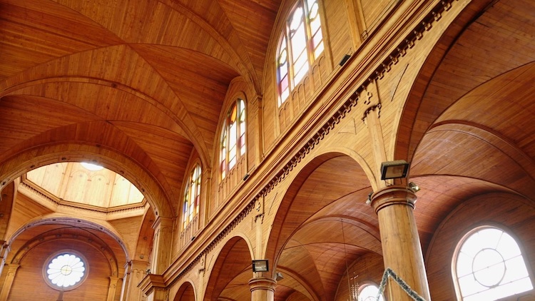 Interior of a wooden UNESCO church on Chiloé Island with arched ceilings and stained glass