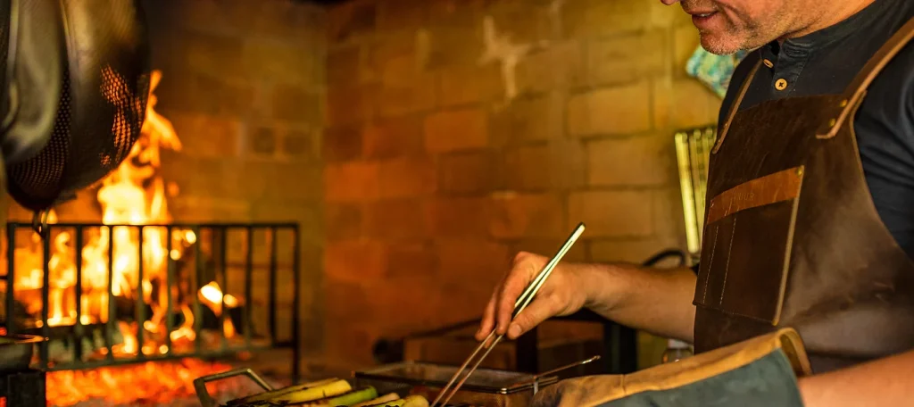 Chef cooking over open fire at Vuur restaurant, Dining in Cape Town