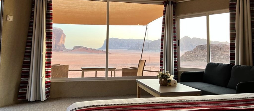 Inside a desert tent, large windows frame sweeping views of Wadi Rum’s red sands and towering rock formations.