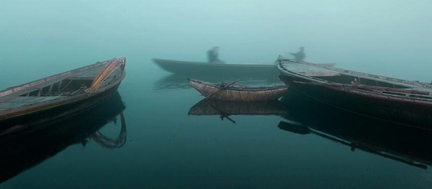 Three boats on the Ganges in Varanasi on a misty morning.