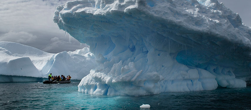 Zodiac and tourists are dwarfed by huge icebergs in Antarctica