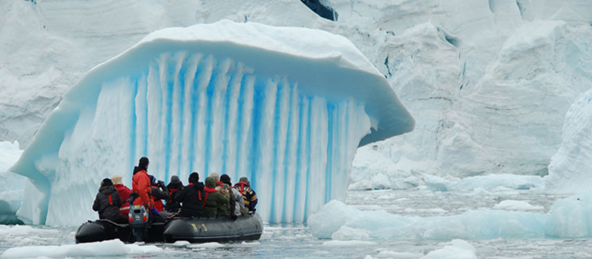 Tourists view beautiful blue icebergs from a Zodiac in Antarctica