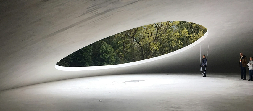 The sculptural interior of the Teshima Art Museum, where light and water interact within a serene concrete space.