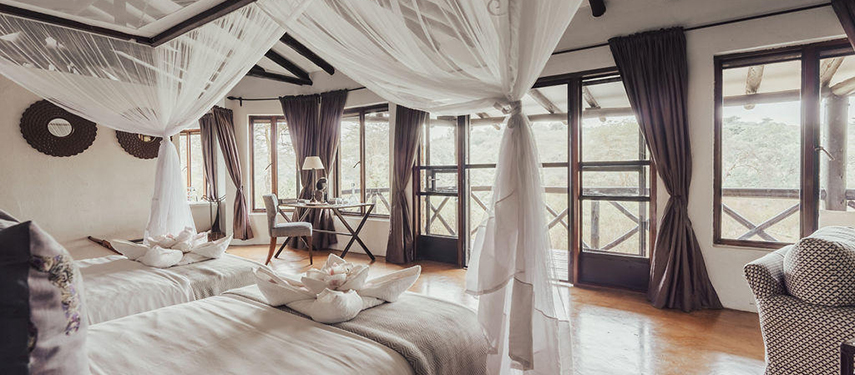 A twin suite at The Emakoko with canopy beds, natural light, and a veranda overlooking the bush.
