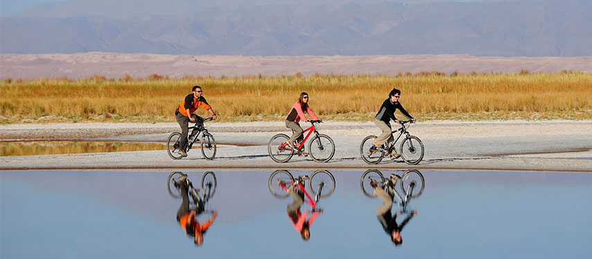 People cycling alongside a lake at Explora Atacama, Chile