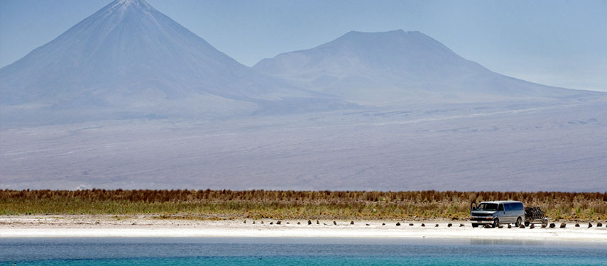 A van parked alongside a lake in the salt pans of the Atacama Desert