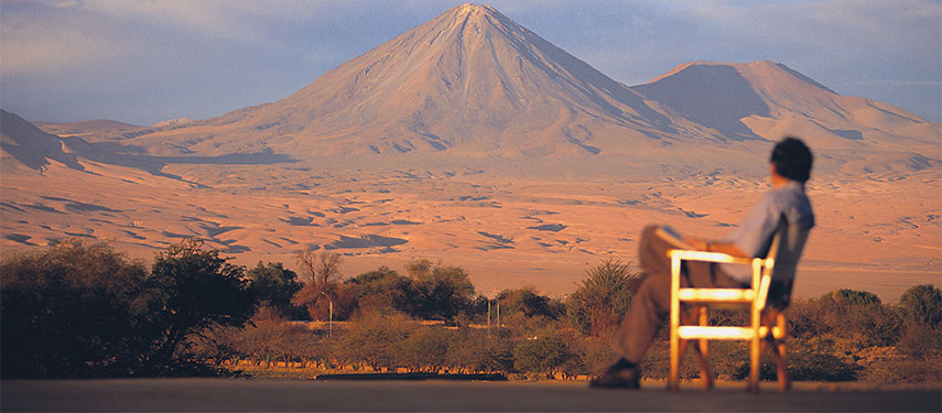 Man at Explora Atacama hotel looking across a lake to a volcano in the distance
