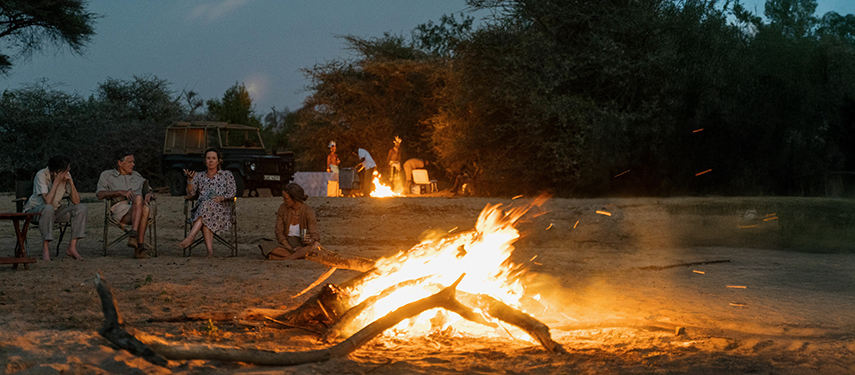 Guests gathered around a glowing firepit under a starry sky during fly camping at Reteti.