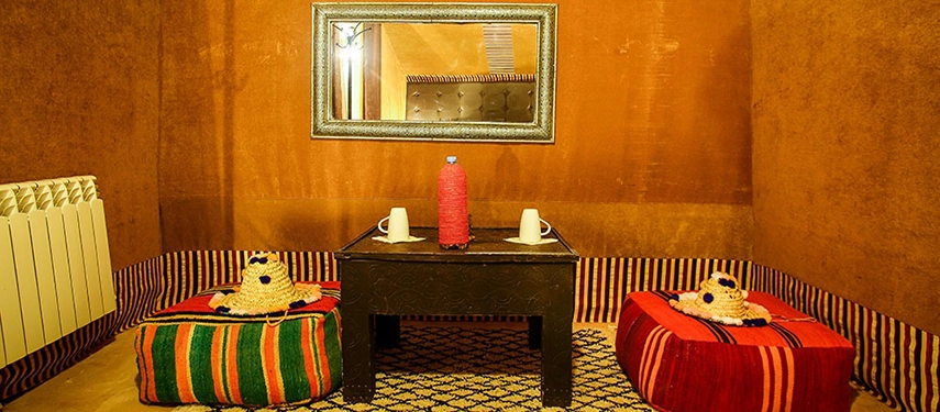 Small desert lounge area with low seating, striped cushions, and a carved wooden table.