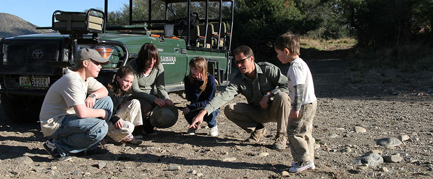 Children listening to a guide pointing to footprints on an African safari