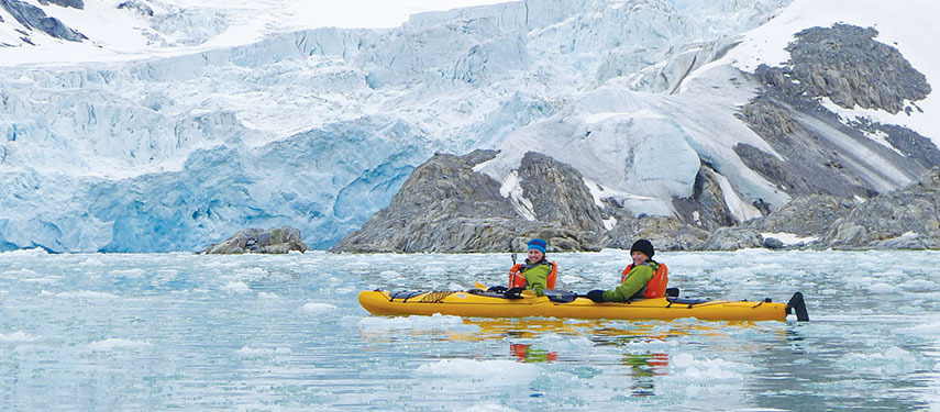 A couple kayaking amongst icebergs in Svalbard, Norway