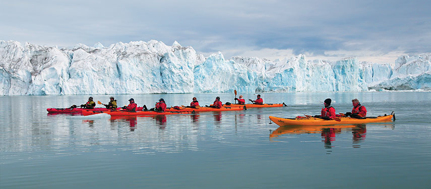 A group of kayakers in Norway with a glacier in the background