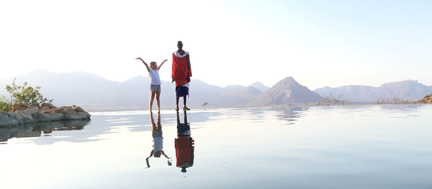 Child standing with a Samburu tribesman at the edge of the pool at Sarara Camp