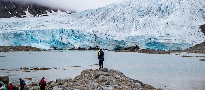Tourist looks across a fjord to a dramatic glacier in Norway