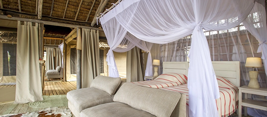 An elegant safari bedroom combines airy canvas walls, natural fabrics and handwoven details with views into Tarangire’s wild landscape.
