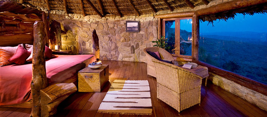 Cosy bedroom at night with raw timber beams and a sumptuous four-poster bed