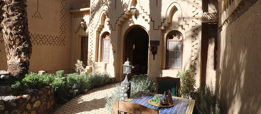 Charming kasbah courtyard with arched doorways, tiled pathways, and a small table set for outdoor dining.
