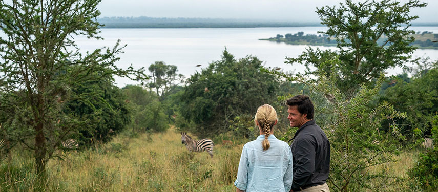 A couple taking in the view across Lake Rwanyakazinga on a walking safari in Akagera National Park, Rwanda