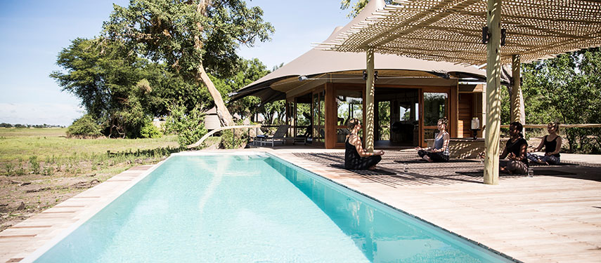 Guests do Yoga By The Pool at Mombo luxury safari camp, Botswana