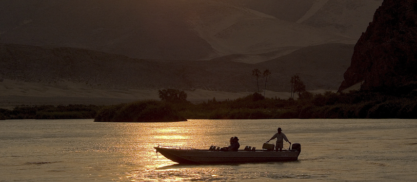 Boating at sunset on the Kunene River in the Serra Cafema Valley, Kaokoveld, Namibia