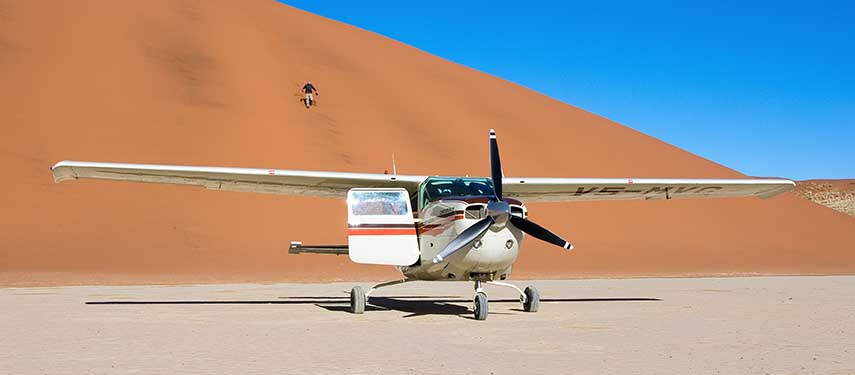 Charter plane grounded in front of a huge red sand dune on a Skeleton Coast Flying Safari