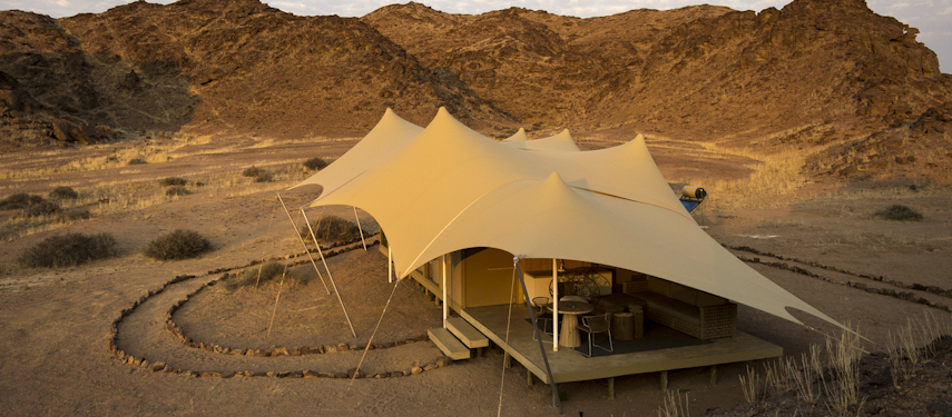 Luxury tents perched in between rugged hills in the desert at Hoanib Skeleton Coast