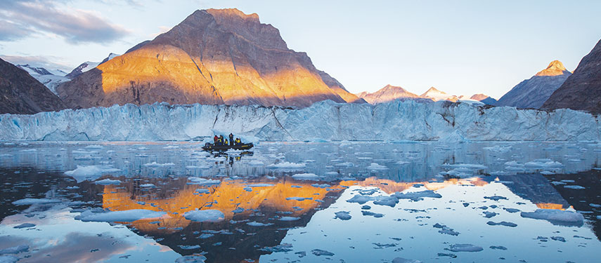 A group of tourists navigate through ice floe in a zodiac in a fjord in Norway