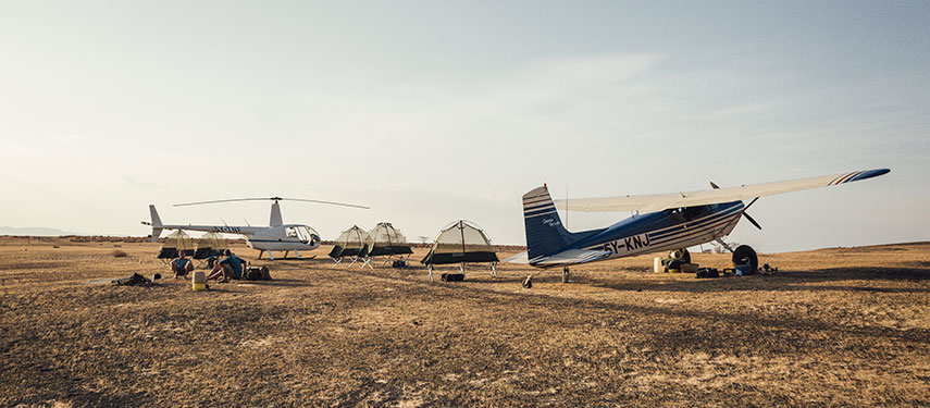 Safari fly camp in Kenya, with a helicopter and light aircraft nerby