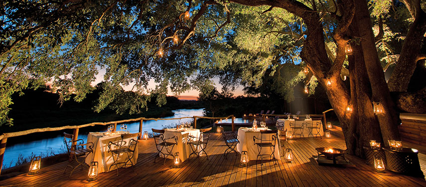 Enjoy a candlelit dinner by the river at Lion Sands Tinga Lodge