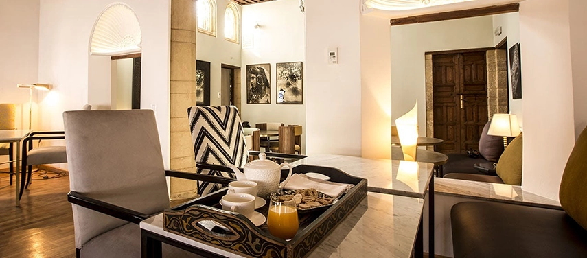 Bright dining space with marble-topped tables, a tray of Moroccan tea and juice, and modern yet traditional décor.